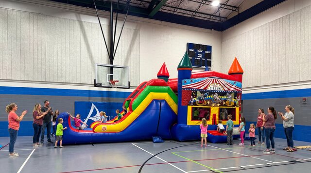 Carnival Super Combo 5-in-1 setup in gym with kids playing and parents watching happily.