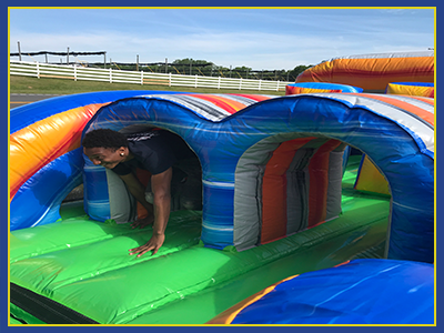 Middle section of a inflatable obstacle course with a person running through a tunnel.