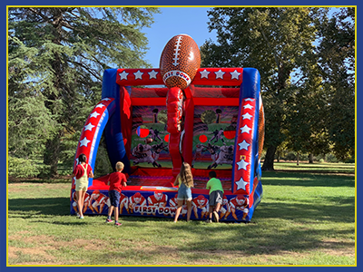 Front view of a football themed interactive inflatable with kids throwing footballs.