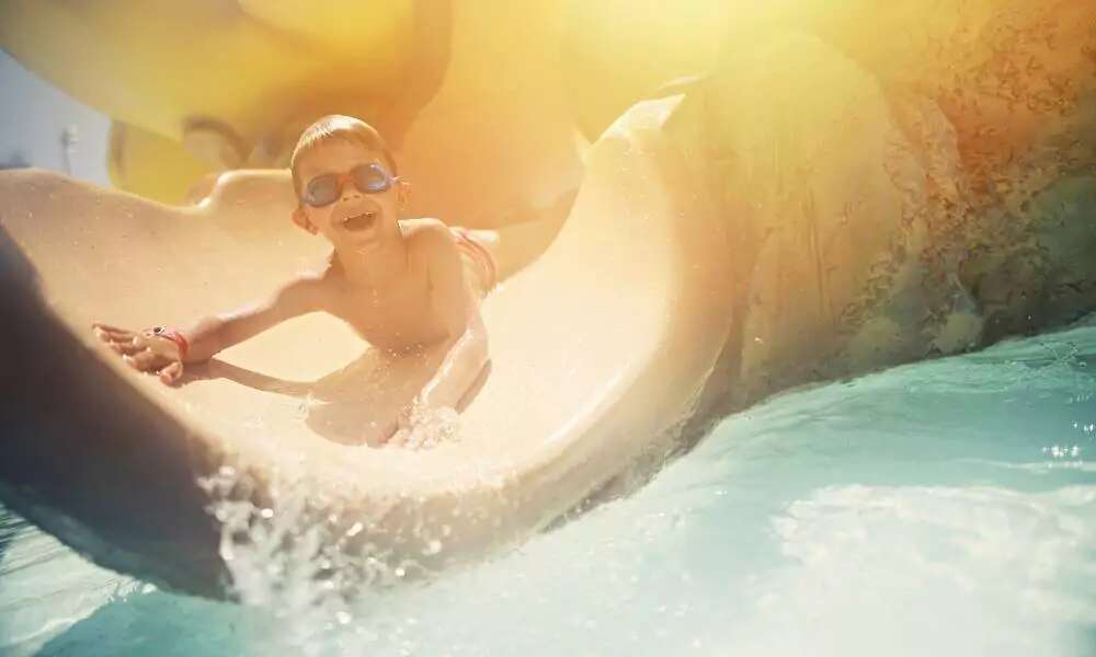 Child sliding into pool water