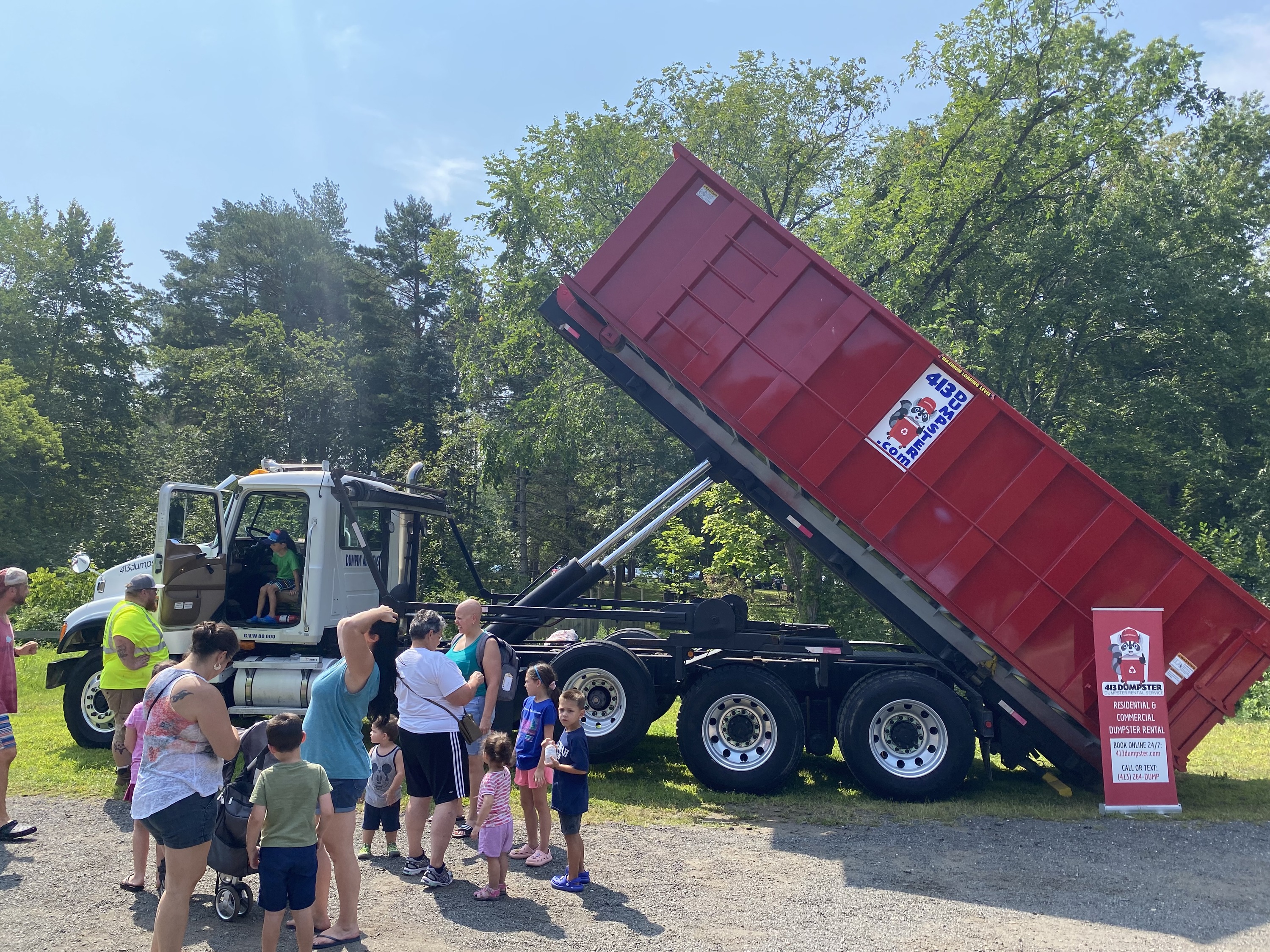 413 Dumpster truck unloading red container at family event