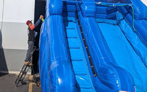 Party With 630 team cleaning and preparing inflatable water slides before delivery at the San Leandro warehouse