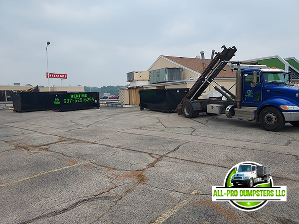 Roll-off dumpster being placed by All Pro Dumpsters truck for a home renovation project