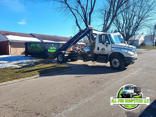 All Pro Dumpsters team member placing a roll-off dumpster at a construction site