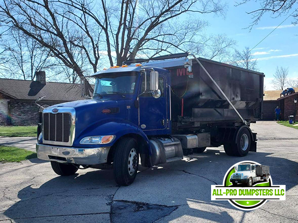 Roll-off dumpster being placed by All Pro Dumpsters truck for a construction project, demonstrating their commercial waste management services