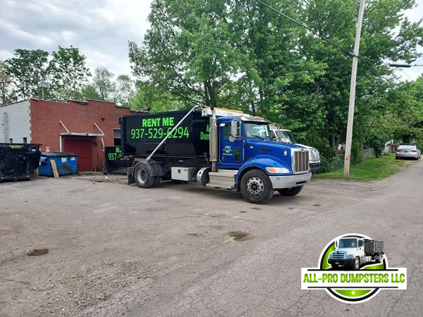 Roll-off dumpster being delivered by All Pro Dumpsters truck to a residential driveway in Dayton, Ohio