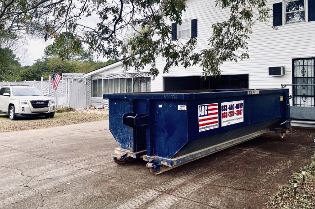 A roll-off dumpster from American Dumpster Company on a residential driveway