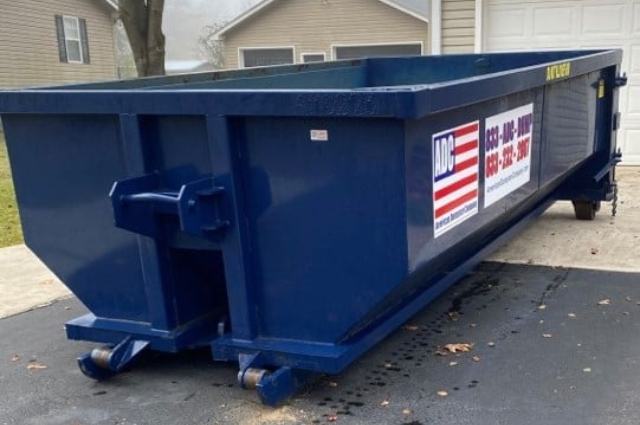 A roll-off dumpster from American Dumpster Company parked on a driveway