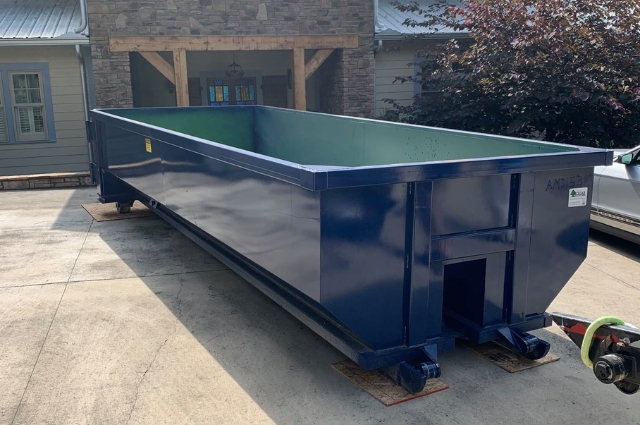 A roll-off dumpster from American Dumpster Company set on a paved lot