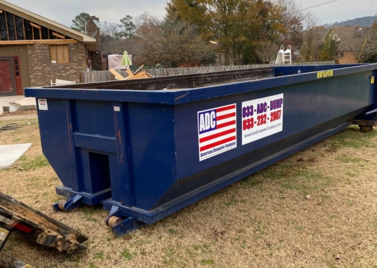 A roll-off dumpster from American Dumpster Company placed on a residential lawn