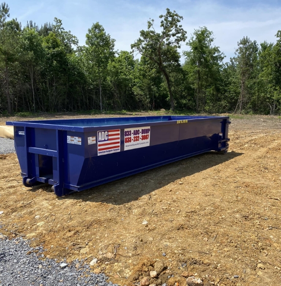 A blue roll-off dumpster from American Dumpster Company on a dirt lot
