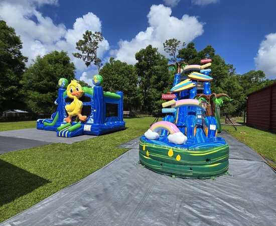 Red and blue inflatable bounce house castle with turrets set up in a parking lot, surrounded by orange safety cones