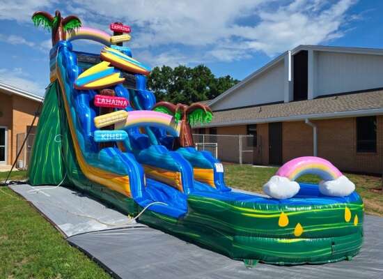 Colorful inflatable obstacle course labeled Adrenaline Rush 3 with slides and crawl-through sections set up outdoors with orange safety cones