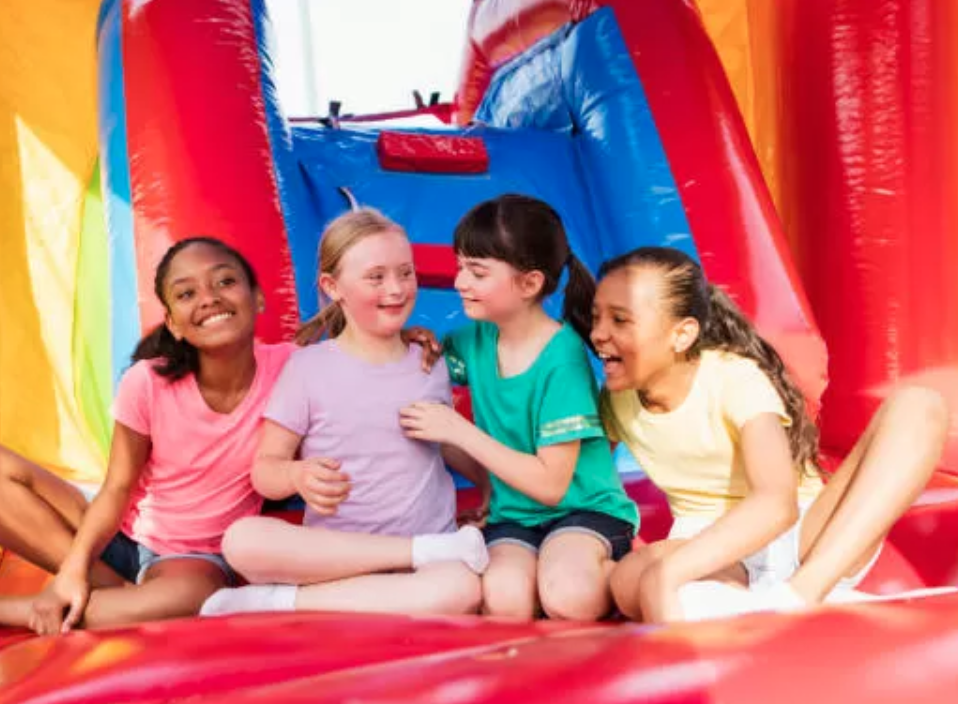 Kids smiling and sitting together inside a colorful inflatable bounce house at a Mansfield, TX party rental event