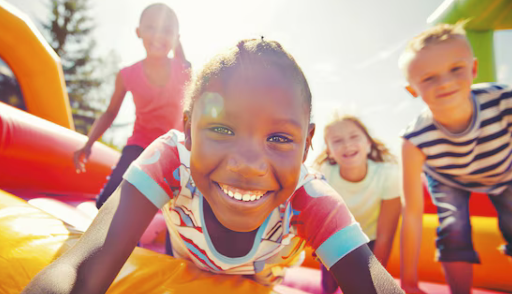 Kids smiling and sitting together inside a colorful inflatable bounce house at a Mansfield, TX party rental event