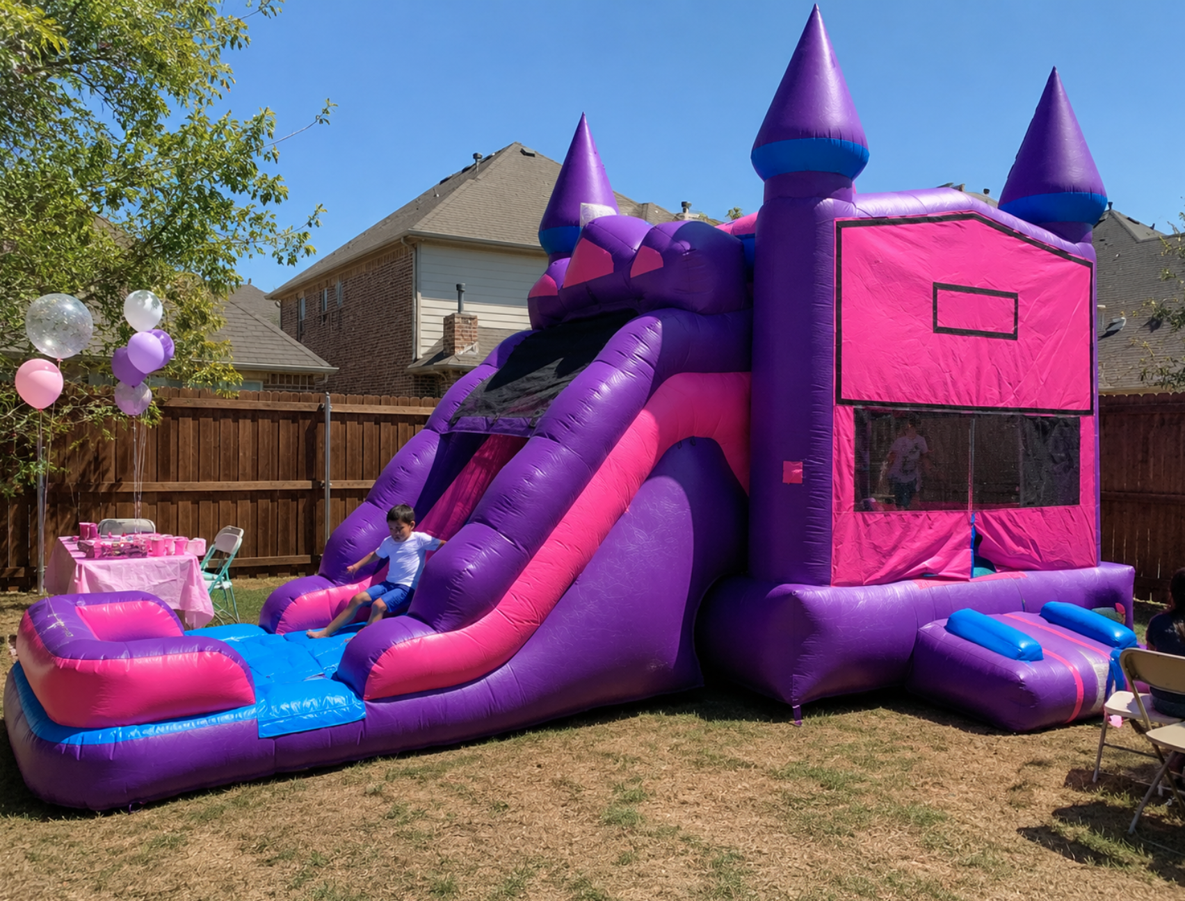 Purple and pink bounce house with slide set up for a backyard birthday party in Grand Prairie, Texas.