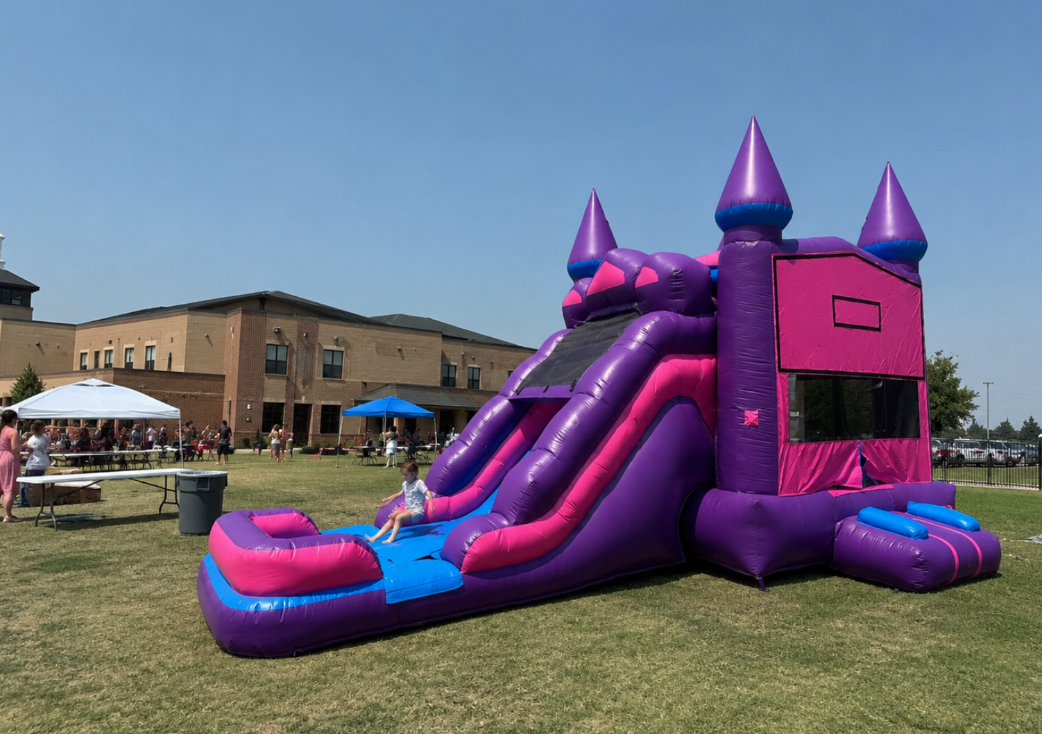 Purple and pink bounce house slide combo set up for a school or church event in Venus, Texas.