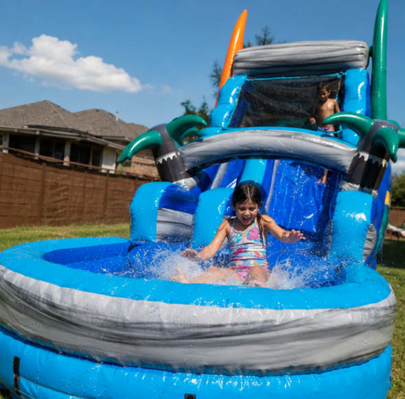 Blue and gray inflatable water slide with tropical accents set up for a backyard summer party with children playing.