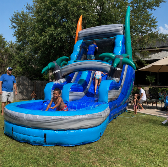 Bright blue inflatable water slide with a splash pool and colorful tropical details at an outdoor family party.