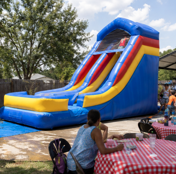 Tall blue inflatable water slide with yellow and red accents set up for a backyard party with kids and adults nearby.