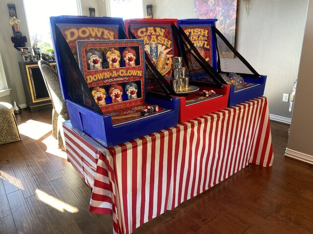 3 carnival games atop a 6 foot table with red and white striped table skirt shown inside of a home.