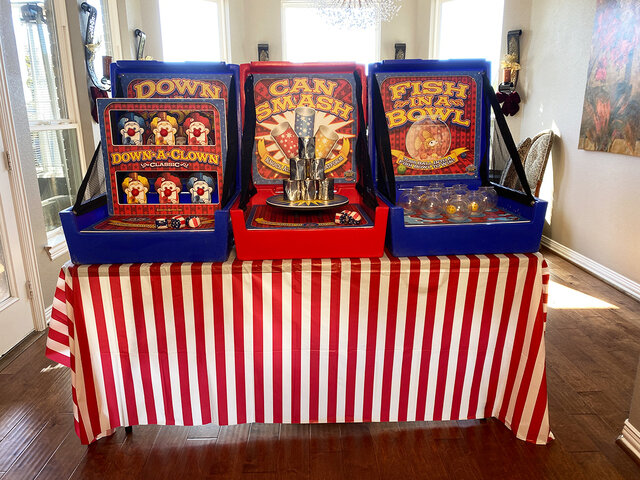 3 carnival case games on a 6 foot table with a red and white striped table skirt shown inside a home.