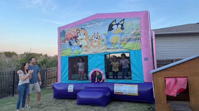 Bluey themed pink sparkly bounce house with kids playing set up outside in Austin Texas.