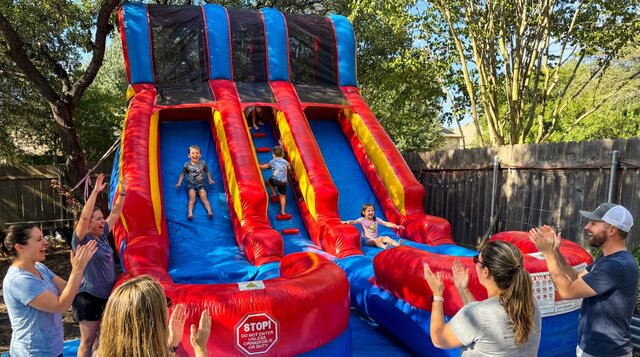 Double Crush Dual Lane Dry Slide with kids playing outdoors with parents smiling on.