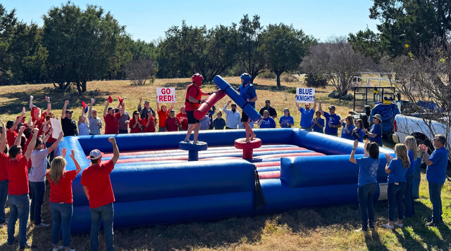 Gladiator Joust inflatable rental setup outdoors with a huge crowd cheering on their team.