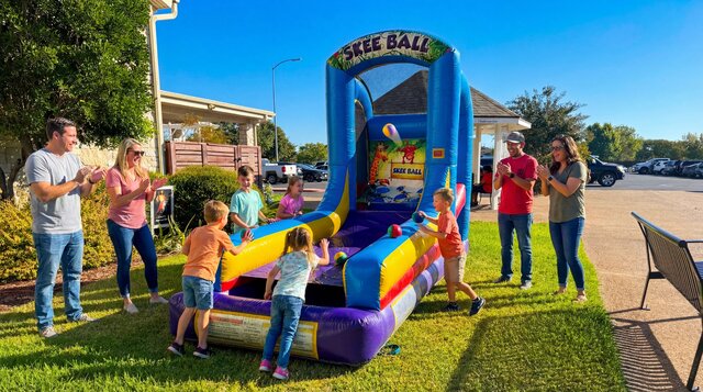 Inflatable Skee Ball Game rental from Austin Bounce House Rentals™ setup outdoors with kids playing on it.