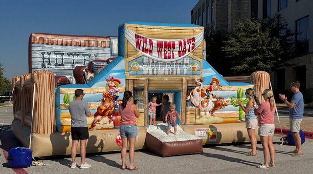 The Wild West Toddler Playland rental from Austin Bounce House Rentals setup outdoors with kids playing and parents watching.