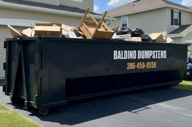 Baldino Dumpsters container holding debris in a neighborhood drivewa