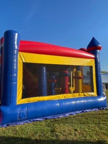 All-in-1 obstacle course slide combo with basketball hoop set up on grass at a Sacramento event from Bouncey House Rentals, castle themed inflatable with blue, red, and yellow exterior