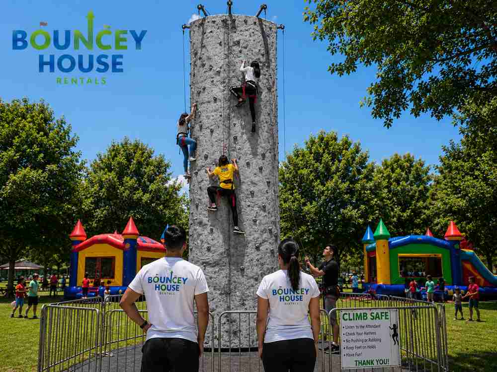 Mobile rock climbing wall rental in Folsom CA from Bouncey House Rentals — 26-foot 5-station portable climbing tower with beginner experienced and professional routes set up outdoors for a school carnival corporate picnic and community event in Sacramento County California