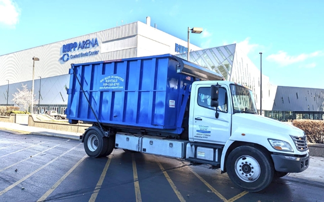 Big Blue Dumpster truck preparing for construction site cleanup and industrial waste hauling