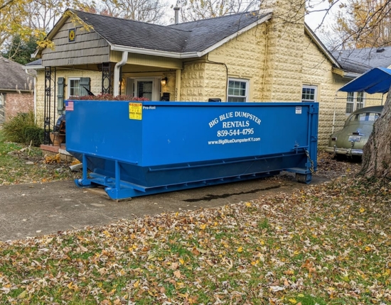 Blue Big Blue Dumpster placed in a residential driveway near a stone house Blue Big Blue Dumpster placed in a residential driveway near a stone house