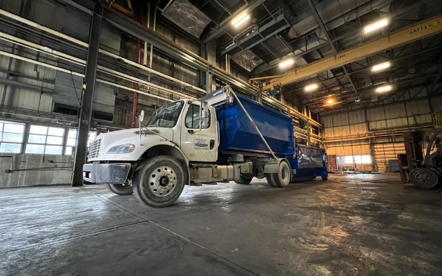 Big Blue Dumpster truck parked inside an industrial warehouse Big Blue Dumpster truck parked inside an industrial warehouse