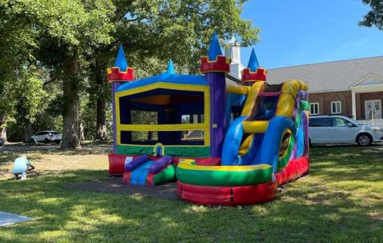 Colorful bounce and slide combo inflatable set up in backyard from Big Bounce Party Rentals