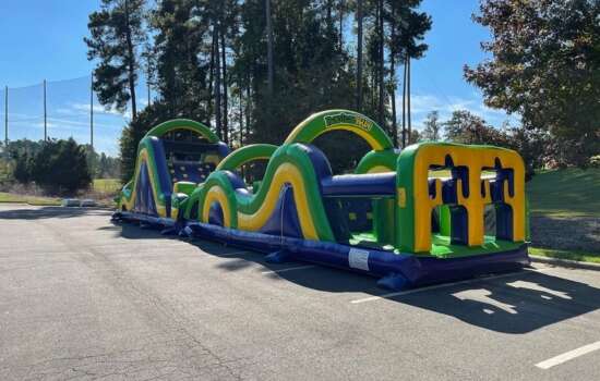 Green and yellow inflatable obstacle course set up outdoors from Big Bounce Party Rentals