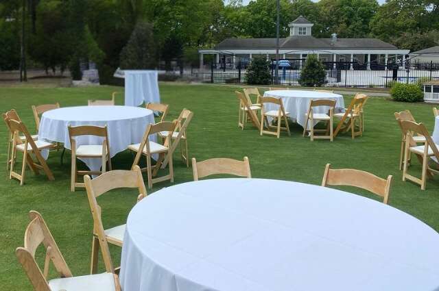 Round tables with folding chairs set up outdoors from Big Bounce Party Rentals