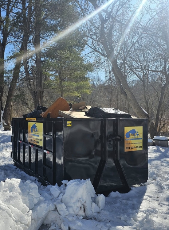 Big Foot Dumpsters roll-off dumpster filled with debris in a snowy outdoor area