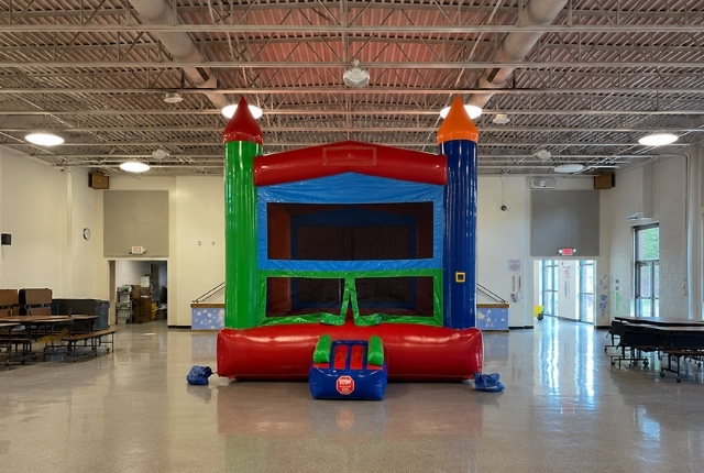Colorful indoor bounce house rental by Boomin Bounce set up inside a spacious event hall