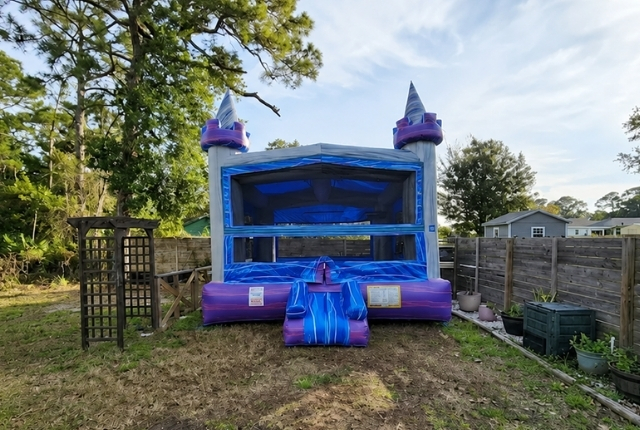 Blue and purple bounce house rental from Boomin Bounce set up in an outdoor backyard area