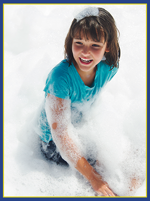 A girl in a blu shirt playing in a foam pit.