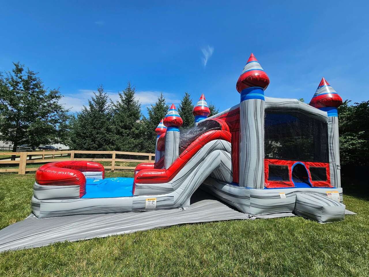 Silver and red castle bounce house with water slide set up by Bounce Buddies Event Rental