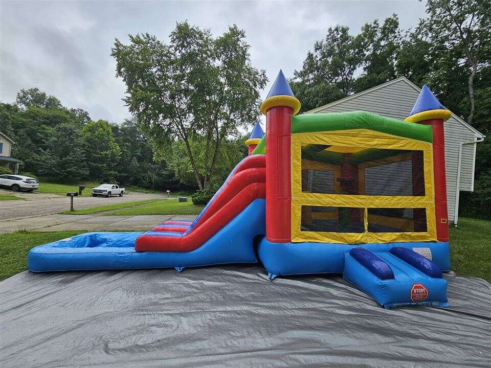 Rainbow castle bounce house combo with slide set up in a backyard in Amelia, Ohio