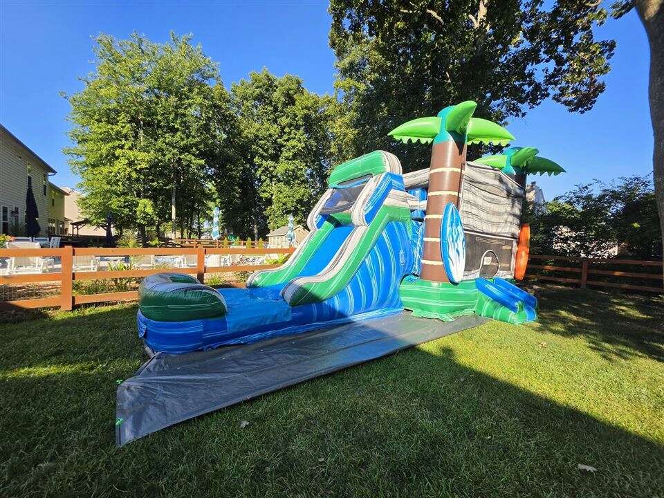 Tropical Cowabunga bounce house combo with slide set up in a fenced backyard in Batavia, Ohio