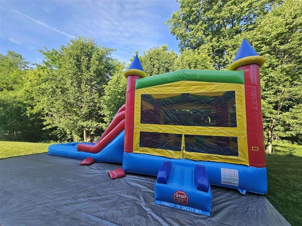 Rainbow castle bounce house combo with slide set up in a backyard in Hebron, Kentucky