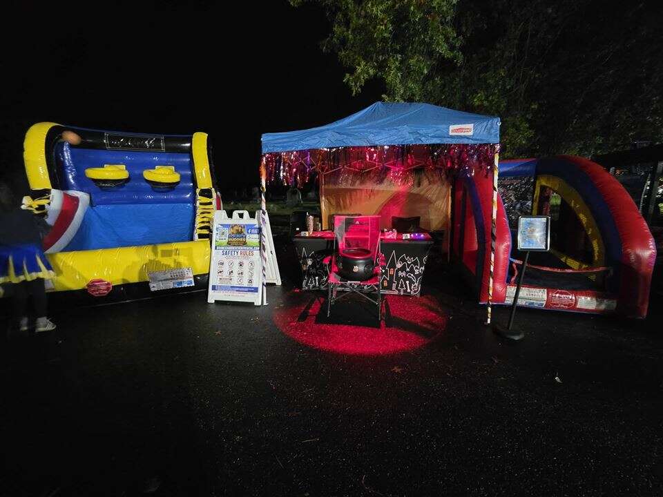 Bounce Buddies booth lit up at night with inflatable games at the St. Louis School Trunk or Treat in Owensville