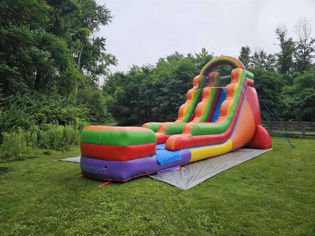 Rainbow inflatable water slide set up in a wooded backyard in Goshen, Ohio